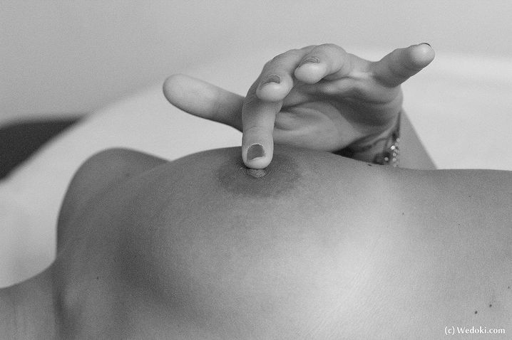 Обнаженная цаца на кровати разминает пизду пальцами черно-белое фото
