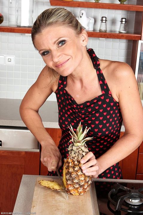 Красивая зрелая тетя с ананасом в руке доводит себя мастурбацией голой пизды до оргазма на кухне